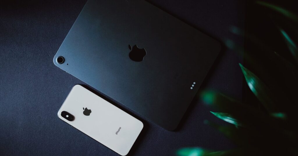 iPad och iPhone liggande på ett mörkt underlag
